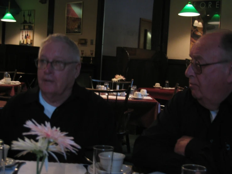 two older men sitting at a dinner table in a restaurant