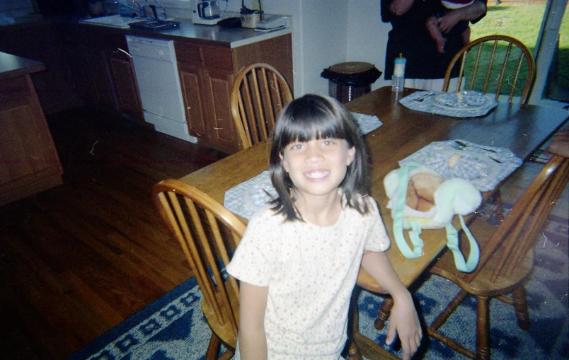 girl sitting at a table in the middle of a kitchen