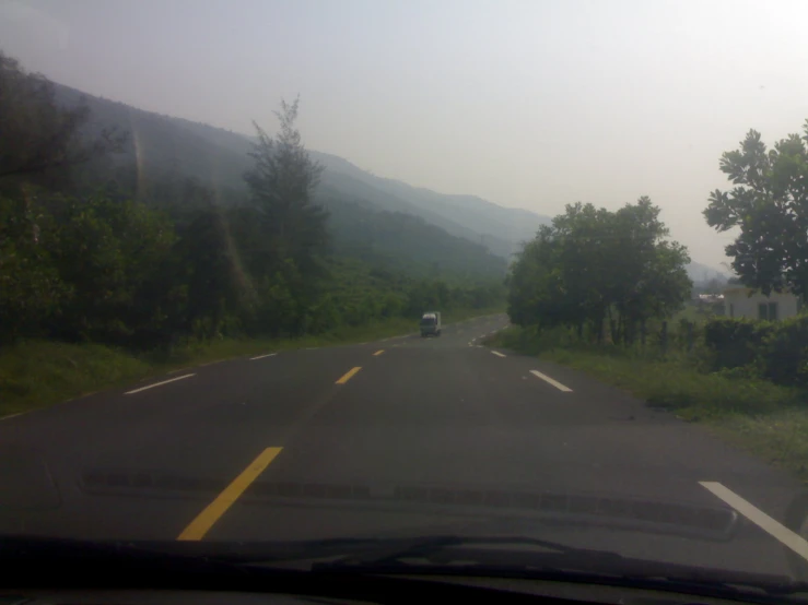 a view out the windshield of a vehicle as a dog drives down a road