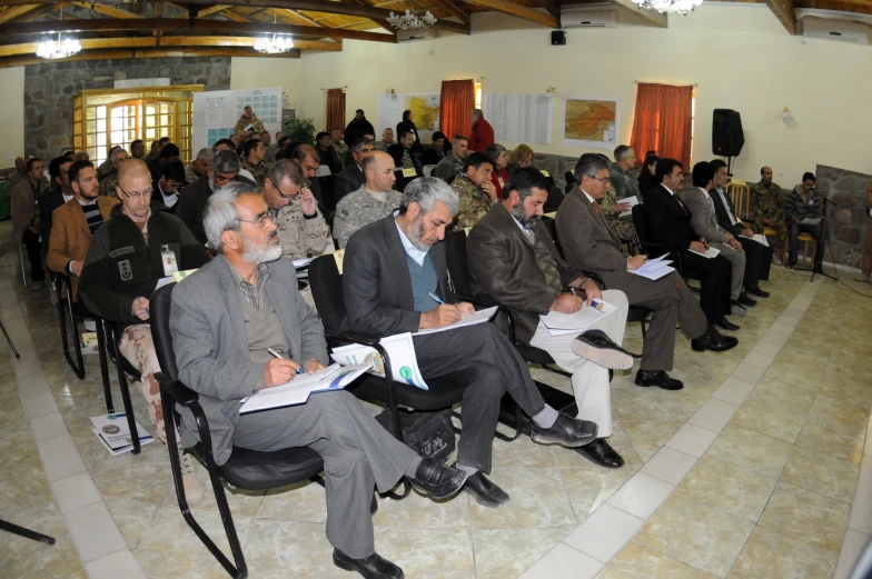 some men in grey suits sitting on chairs with papers