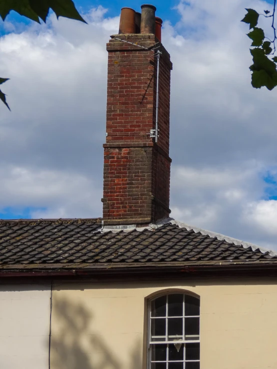 an old brick chimney and window sit against a blue sky