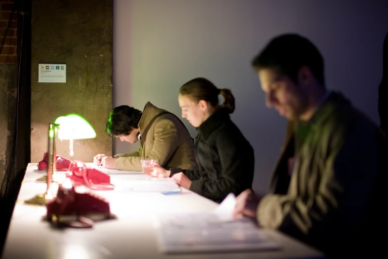 three people are sitting at the table reading papers