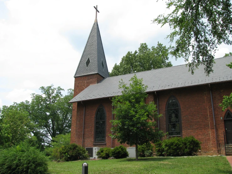 a church with an old steeple stands in the grass