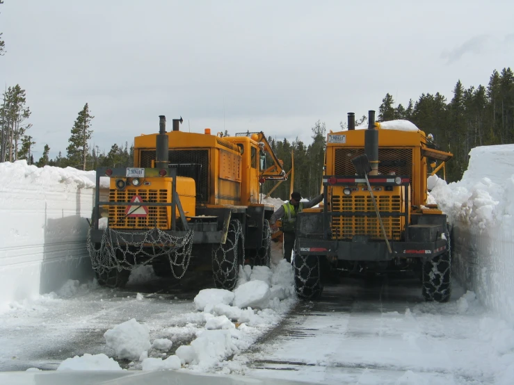 there are two large yellow trucks that are on snow plow