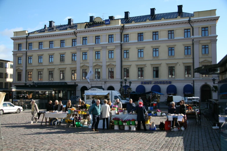 a big building is shown with people standing on the sidewalk