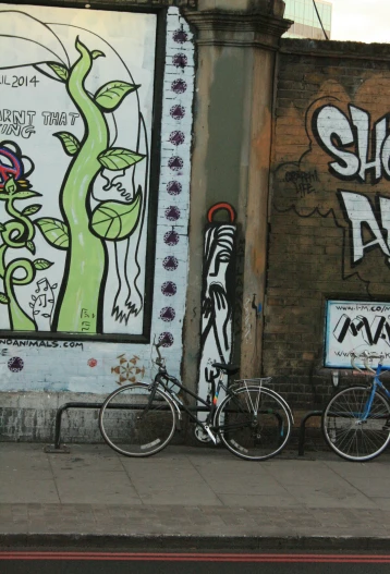 a bicycle parked next to graffiti on the side of a building