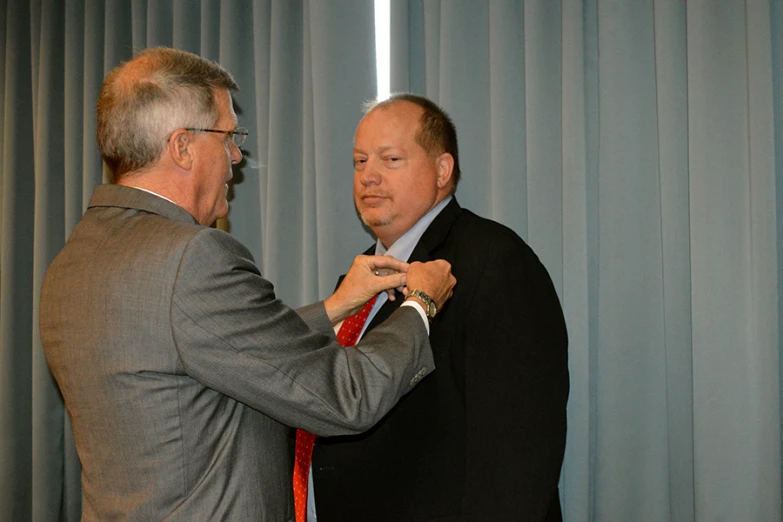 two men in suits straightening their ties by the window