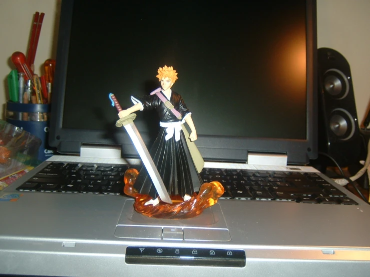 anime action figure sitting on top of a laptop