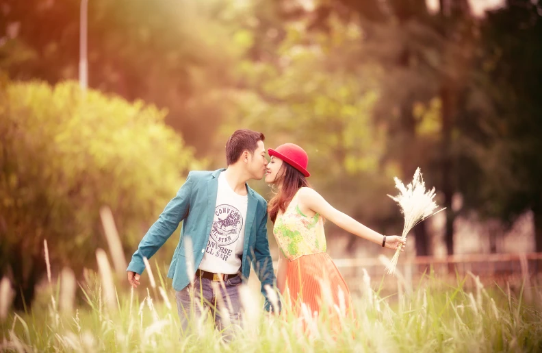 the young man and woman are kissing in the tall grass
