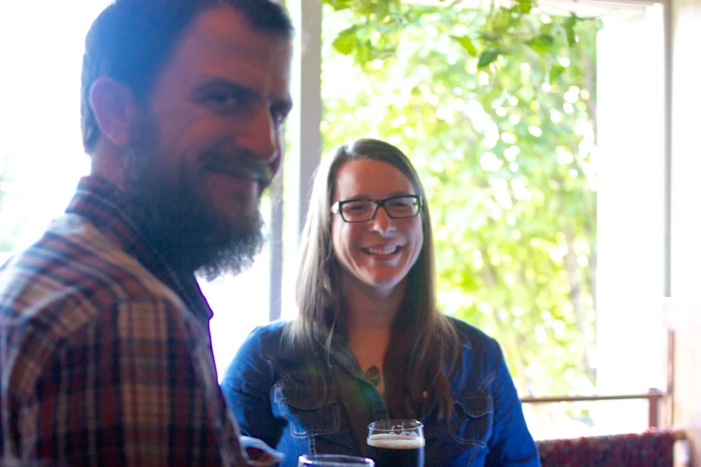 a man and woman are smiling at the camera while drinking