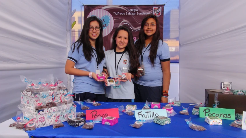 three girls are holding paper cutouts at the table