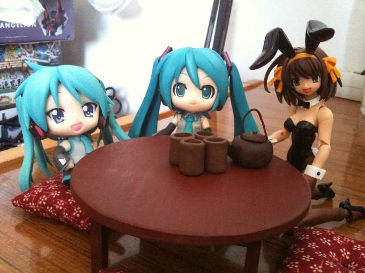 some anime dolls are sitting around a wooden table