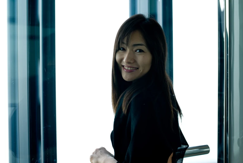 an attractive young woman standing next to a window