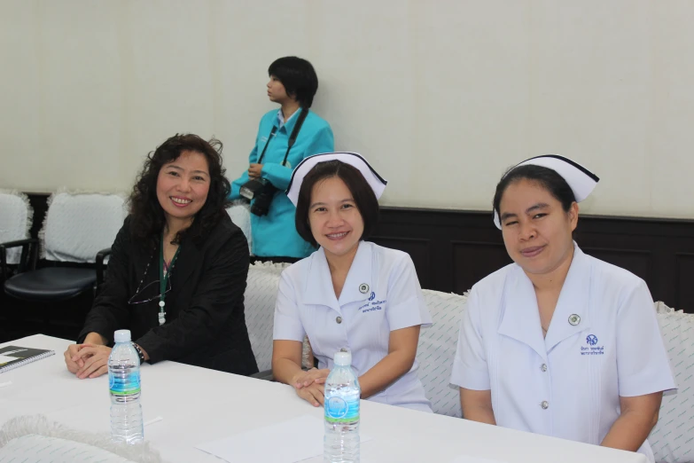 three female nurses sitting at a table posing for a picture