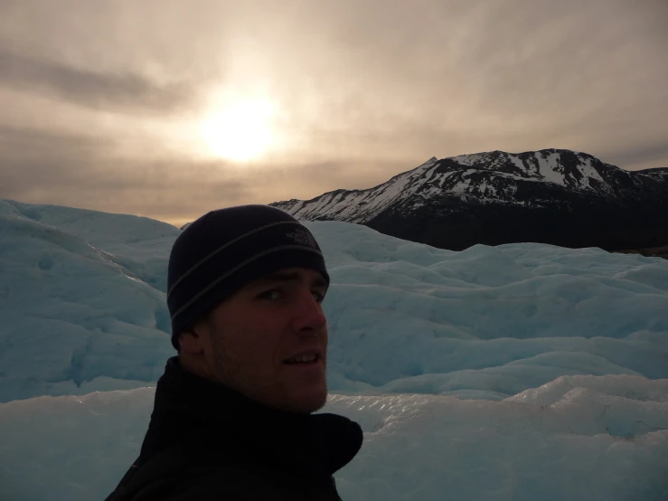 a man wearing a beanie standing in front of some snow