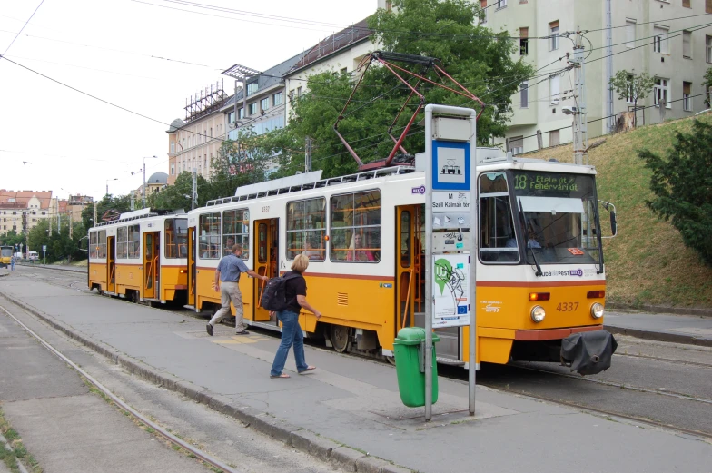 people at a bus stop that is yellow and white