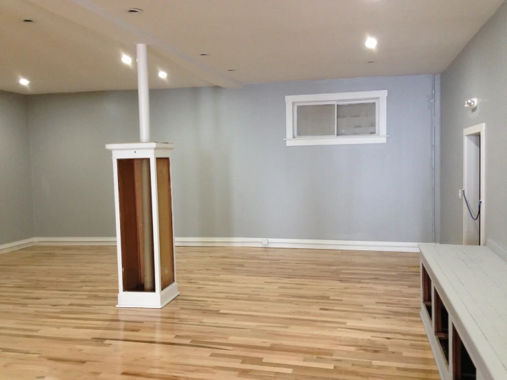 an empty room with hardwood floors, a window, and a heater