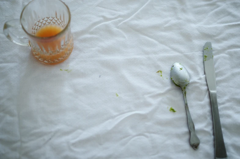 an empty glass next to a spoon and a plastic measuring spoon