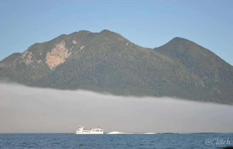 the boat is traveling near the green mountain