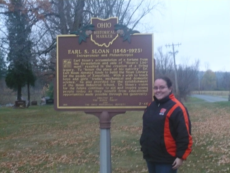 there is a woman standing next to the sign