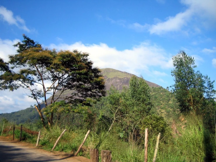 a street going uphill next to a mountain and grass