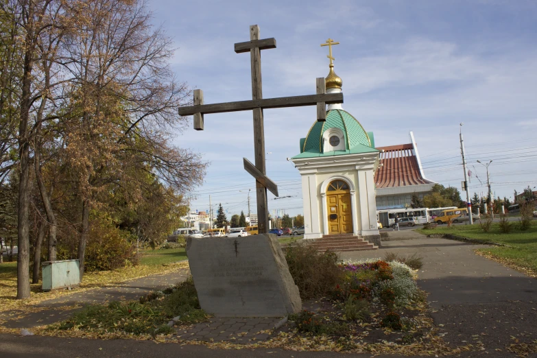 a very large cross outside of a church with a few people on the grass