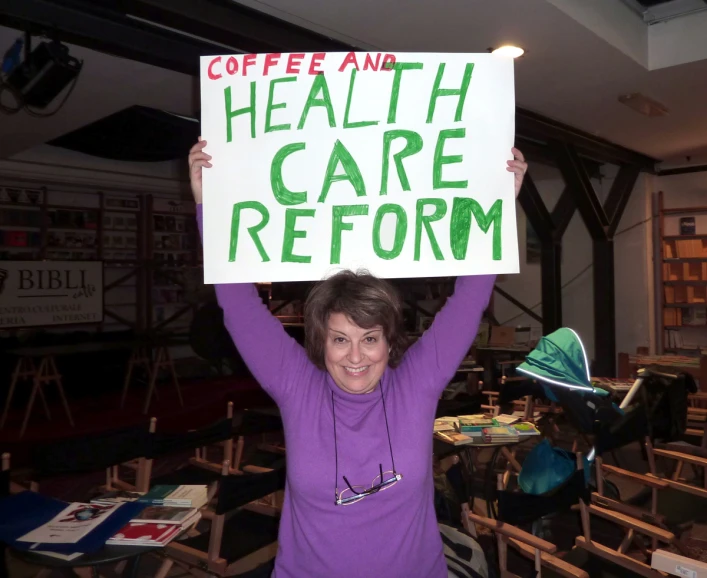 a woman holding a sign that says coffee and health care platform