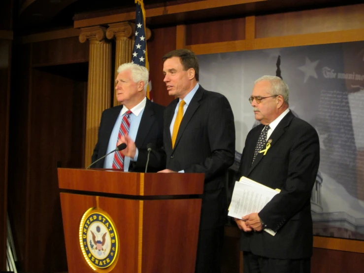 three men standing behind a podium at an event