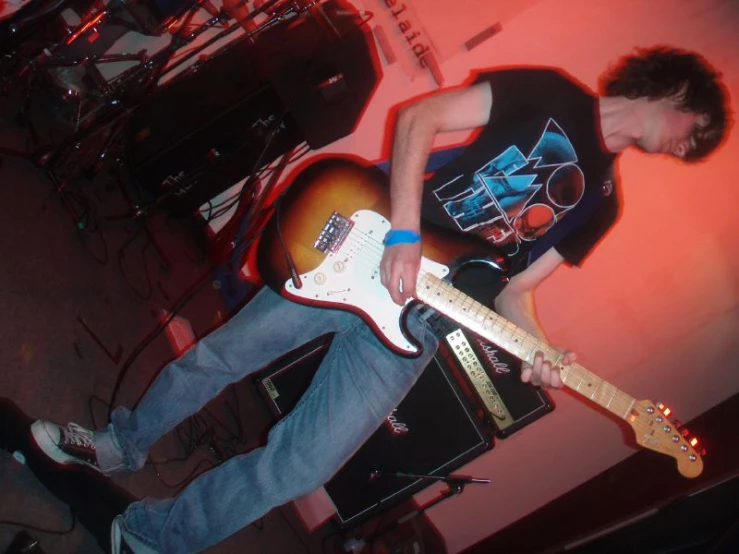 man with guitar in hand on stage playing