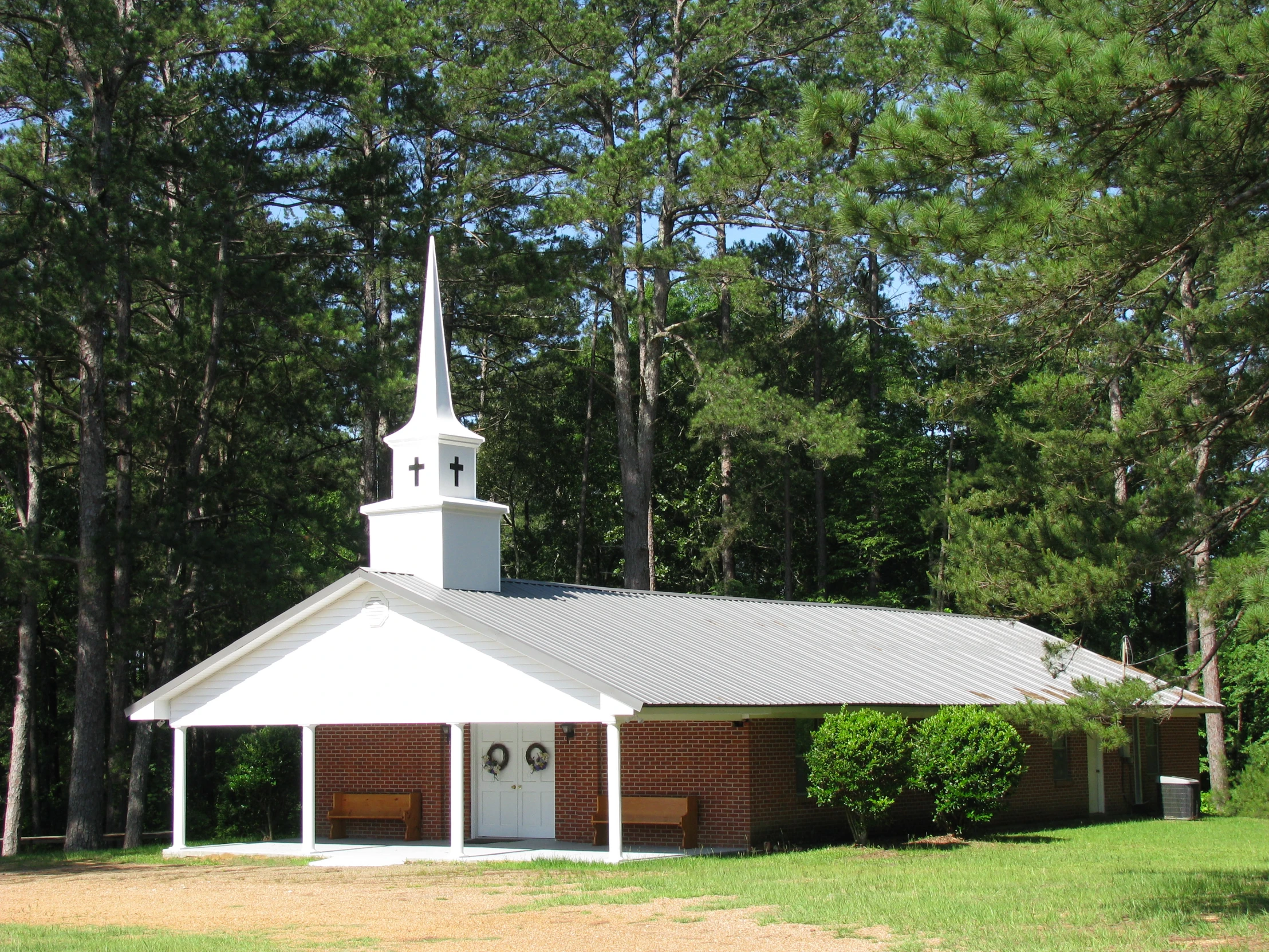 a small church surrounded by trees on a sunny day