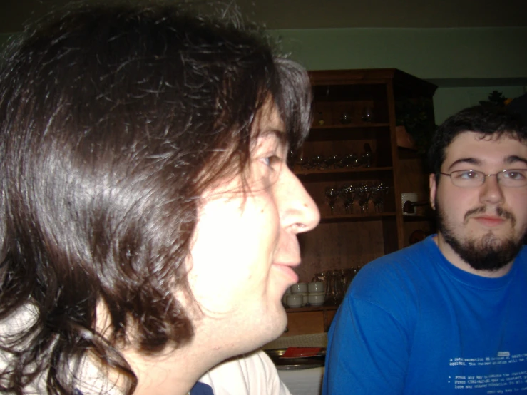 two people sitting near each other in front of a wooden cabinet