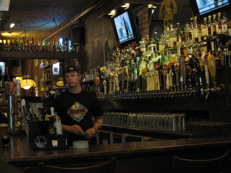 the bartender is behind the bar watching several sports games