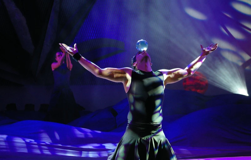 a man with his arms outstretched in front of a lit stage