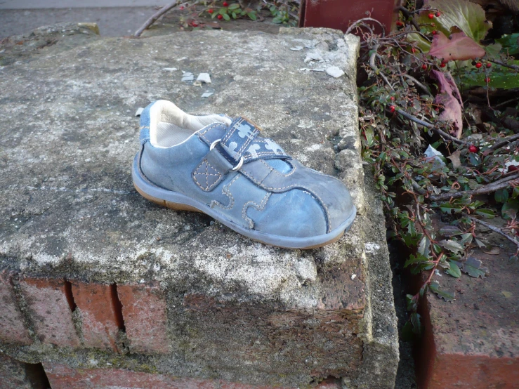 a blue sneaker sitting on a concrete slab