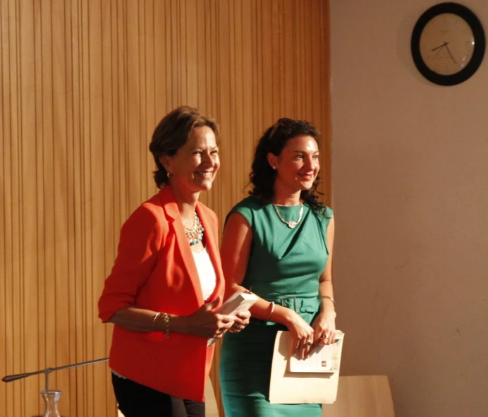 two woman standing next to each other and talking to the camera