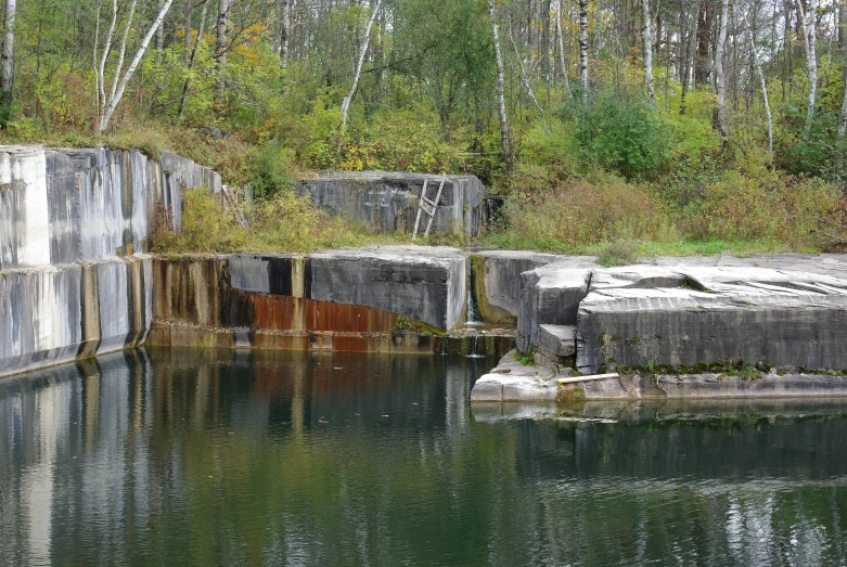 an old cement ramp over water with a fallen tree behind it