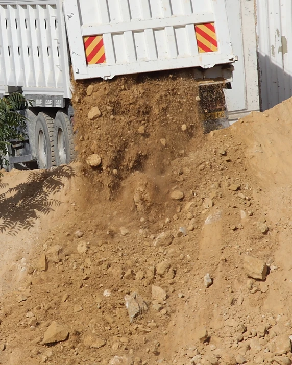 the back end of a truck that is driving on a dirt road