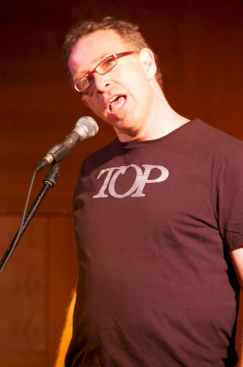 a man in glasses and a brown shirt is on stage