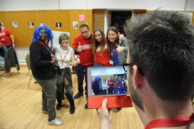 a group of people taking pictures on a digital device