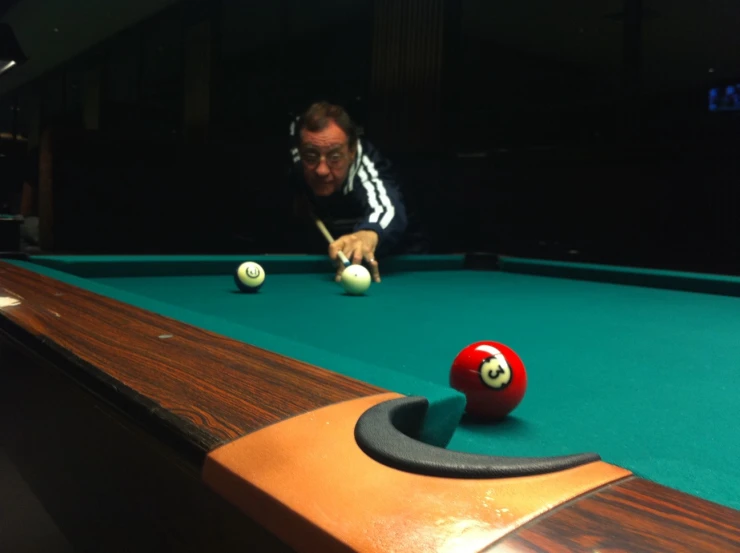 a man leaning over a pool table with a pool ball