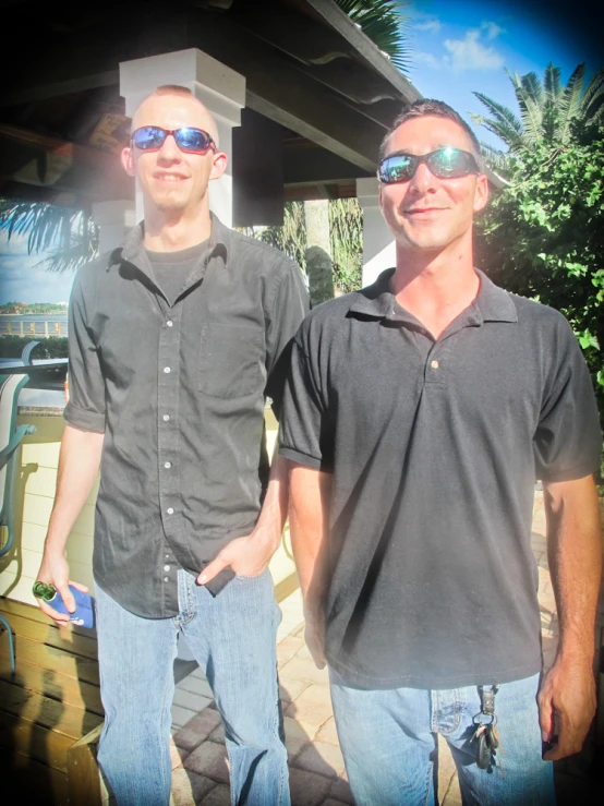 two men stand next to each other, with sunglasses on