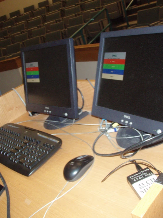 two computer monitors sitting on top of a wooden table