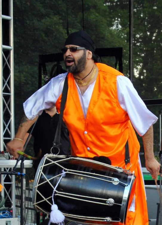 a man in a large orange outfit holding a drum