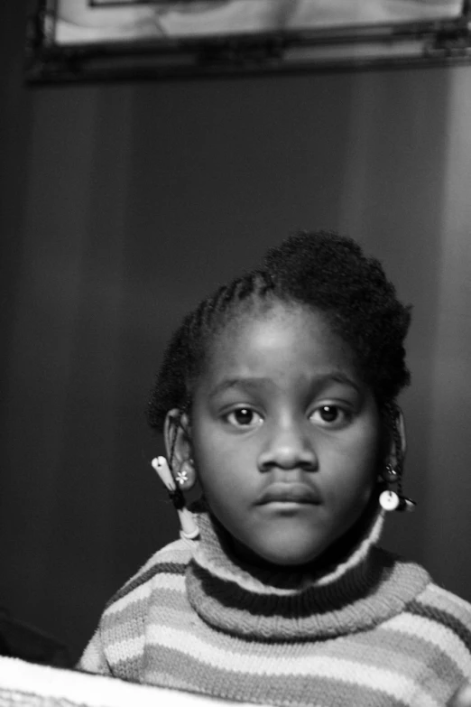 a little girl with big earrings sitting and looking away from the camera