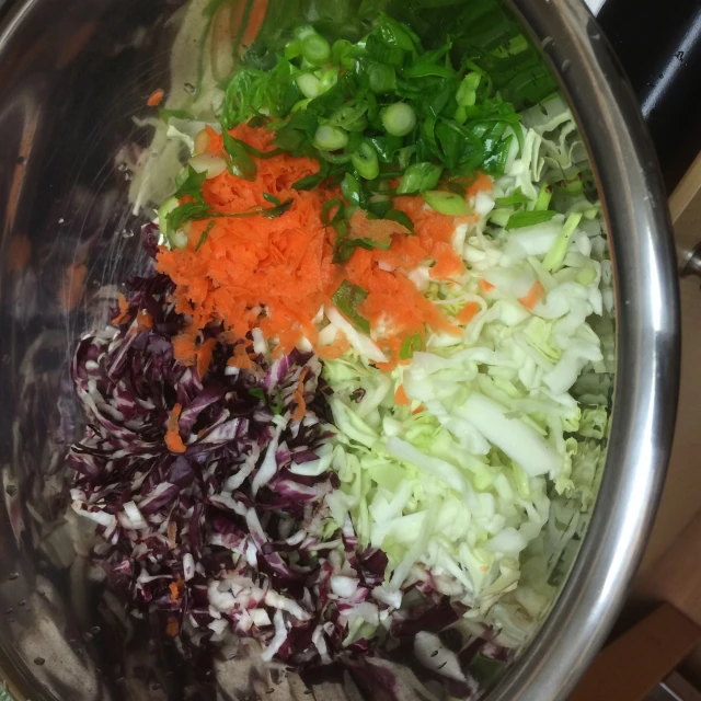 various vegetables are in a silver bowl on a stove