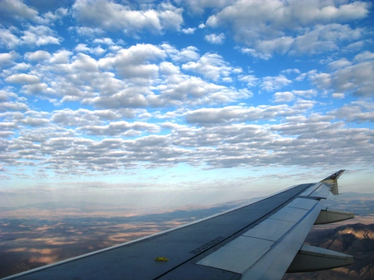 view from plane with a wing in the foreground and clouds in the background