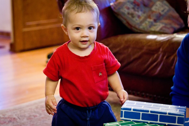 a little boy holding onto a blue and green house with bricks all over it