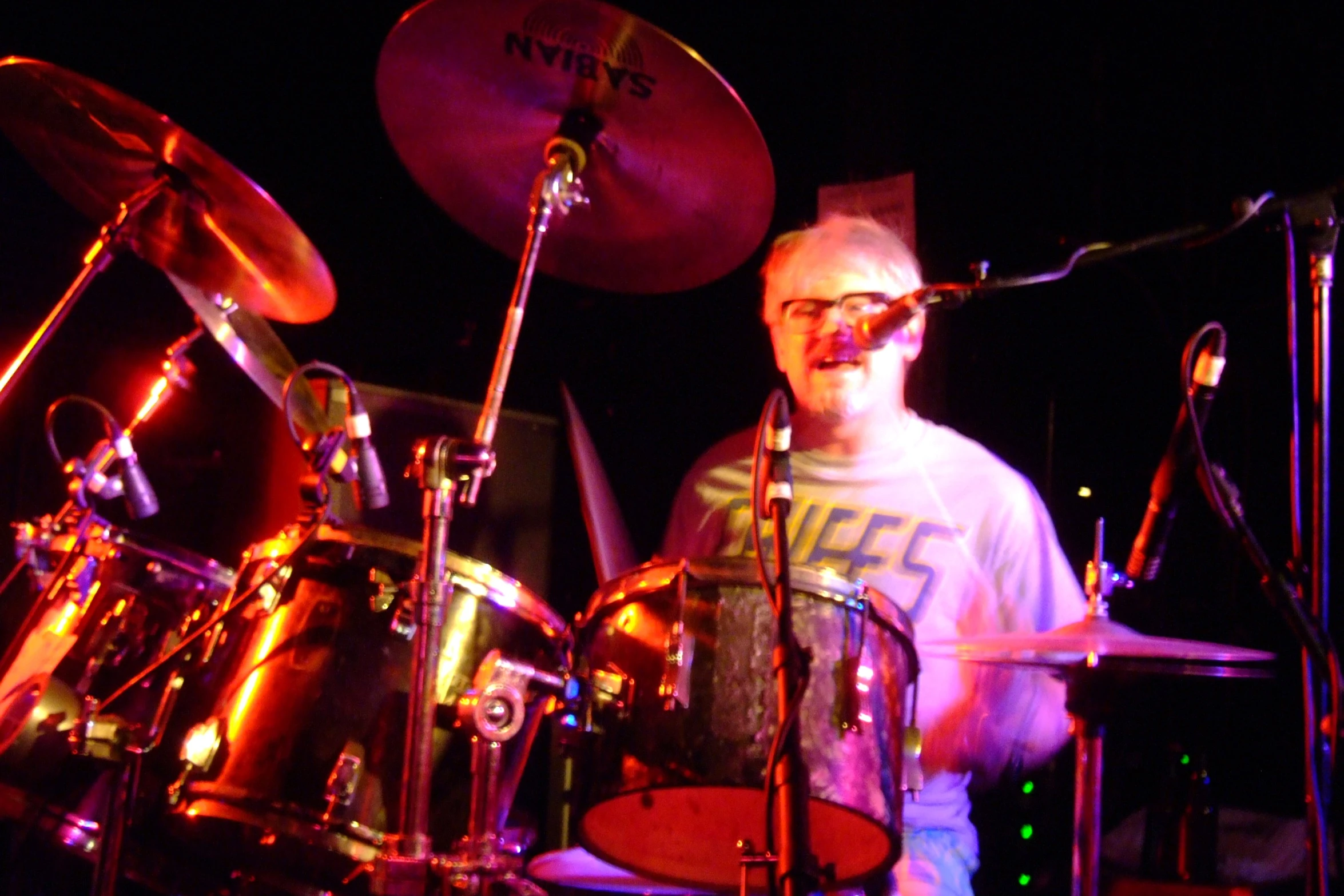 a man sitting in front of drums on stage