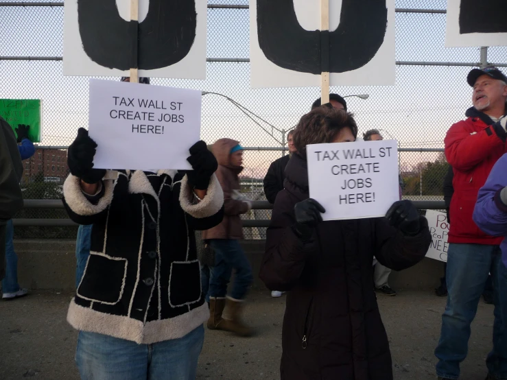 a group of people holding up signs in front of a fence