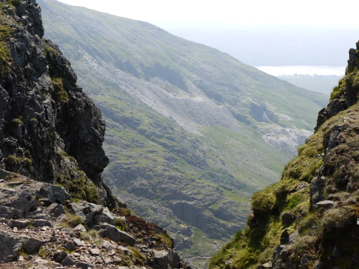 a person hiking up a steep hill with a large body of water below